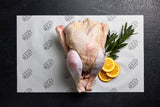 A whole raw turkey displayed on a white paper with the brand name 'Australian Meat Emporium' on it, accompanied by decorative orange slices and a sprig of herbs.